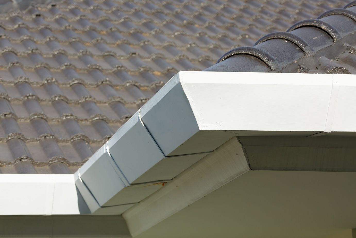 dark brown tile roof and white gutters 