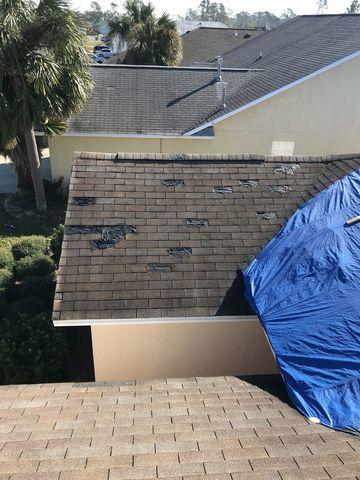 storm damaged roof with a blue emergency roof tarp