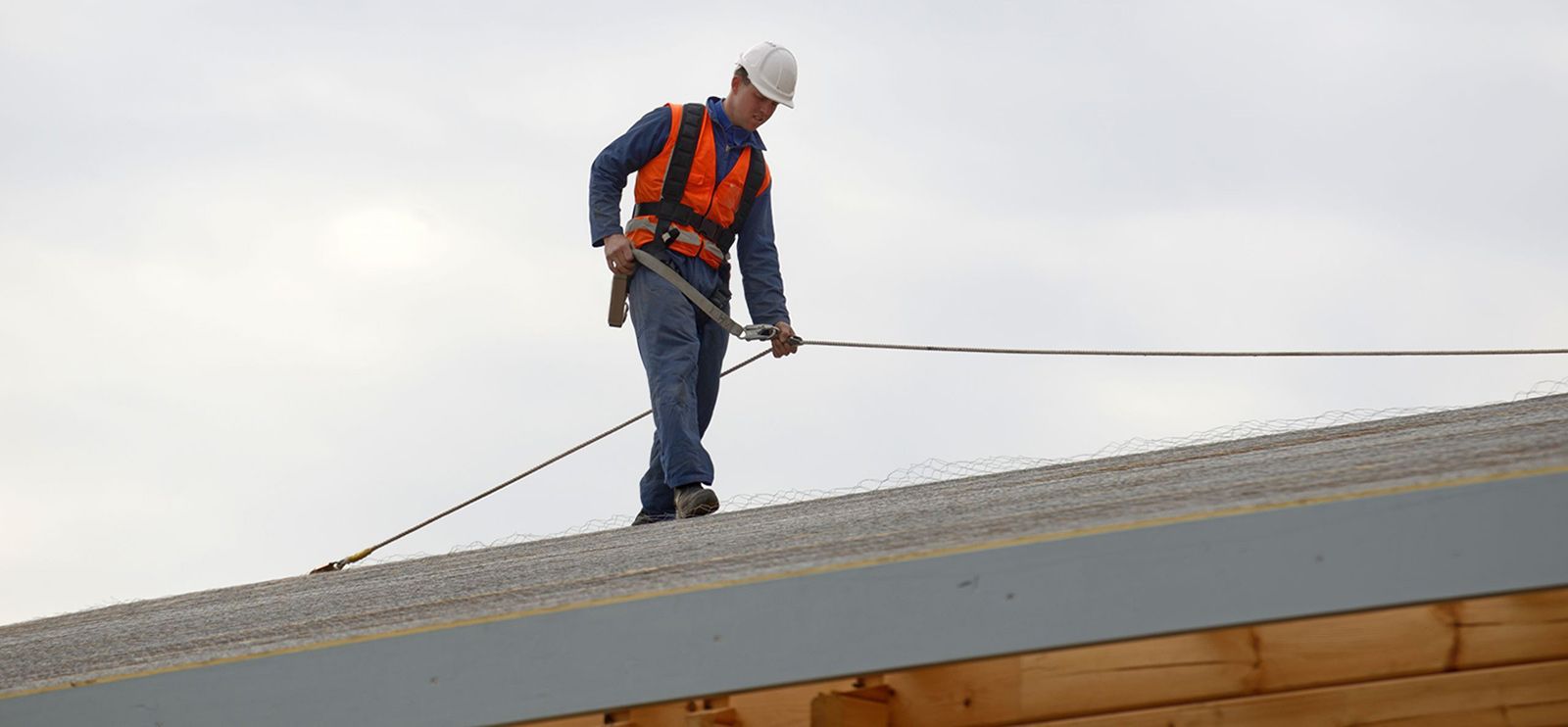 Man doing a roof inspection wearing a rope and safety harness