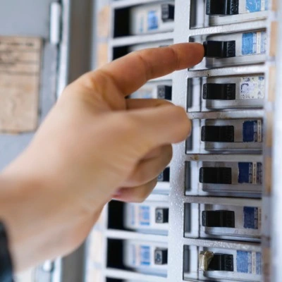 Hand pointing at electrical circuit breakers in panel box during home inspection