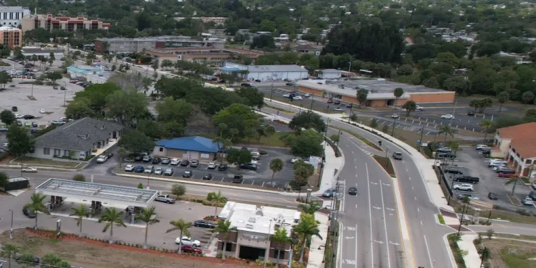 An aerial view of a Florida commercial district featuring various buildings with flat TPO roofs, sloped asphalt shingles, and large retail centers requiring commercial roof maintenance.