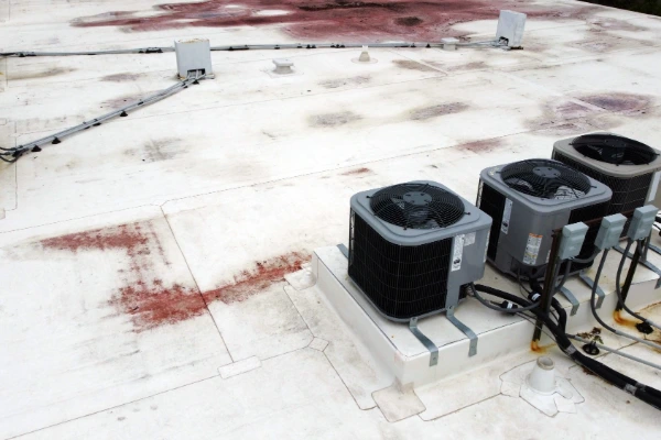 Commercial TPO flat roof with HVAC units showing rust stains and membrane wear in need of commercial roof repair
