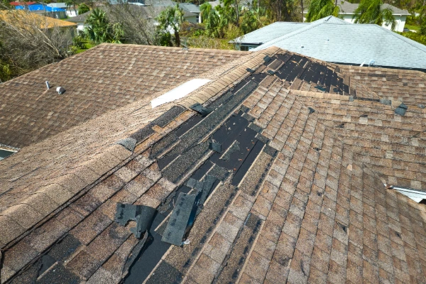 Aerial view of severe hurricane wind damage on a Central Florida asphalt shingle roof with large sections of shingles torn away