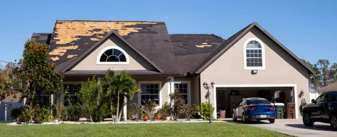 Aerial view of a Florida home with large sections of shingles missing after storm damage, exposing the wood decking underneath