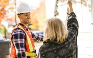 Roofing contractor speaking with a homeowner during a free estimate visit before a roof inspection.