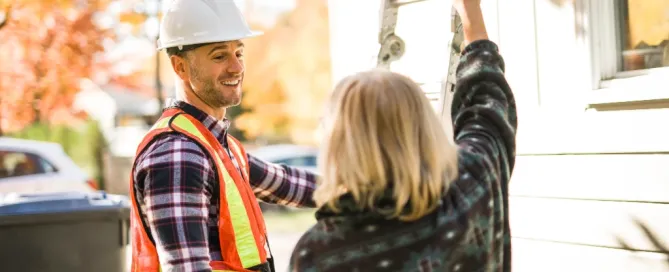 Roofing contractor speaking with a homeowner during a free estimate visit before a roof inspection.