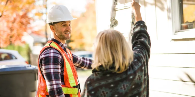 Roofing contractor speaking with a homeowner during a free estimate visit before a roof inspection.