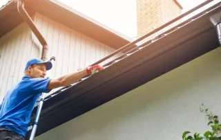 Roofing technician inspecting gutters during preventive roof maintenance