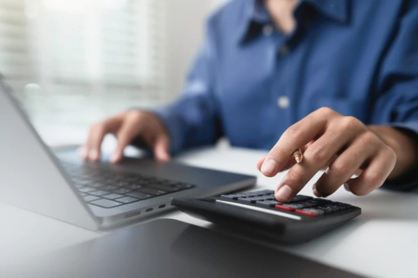 Homeowner using a calculator and laptop to plan roof replacement financing